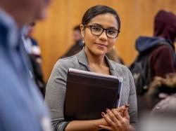 photo of student wearing glasses holding folder at career fair olding fol